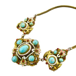 Peut inclure: Un collier en or avec une cha&icirc;ne et trois pendentifs en turquoise et en rouge. Les pendentifs sont orn&eacute;s et pr&eacute;sentent des d&eacute;tails complexes.