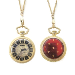 Bucherer 25 mm halsbandsklocka/Fleur de lis-motiv/Röd emalj/Förgylld/Mekanisk uppdragning med 17 juveler/28" lång kedja/