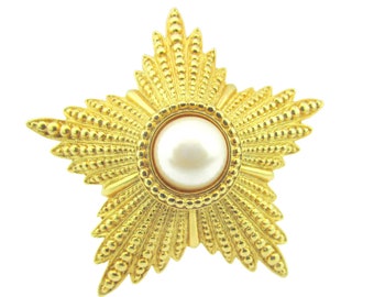 May include: A gold starburst brooch with a large, white pearl in the center.