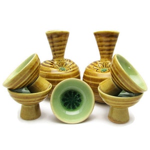 May include: Set of seven ceramic drinking cups and two ceramic vases. The cups are green and brown with a floral design. The vases are brown with a floral design.