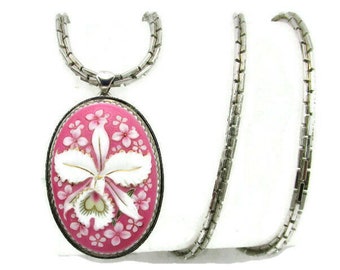Op de afbeelding: Een zilveren ketting met een roze en witte porseleinen hanger met een gedetailleerd ontwerp van een orchidee.