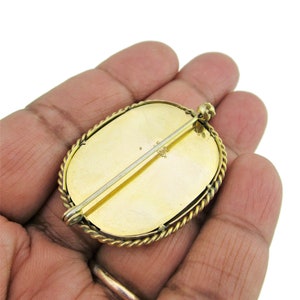 Puede incluir: Broche ovalada de oro con un borde de cuerda. La parte posterior de la broche tiene un pasador y una marca que dice "1/10 14K".
