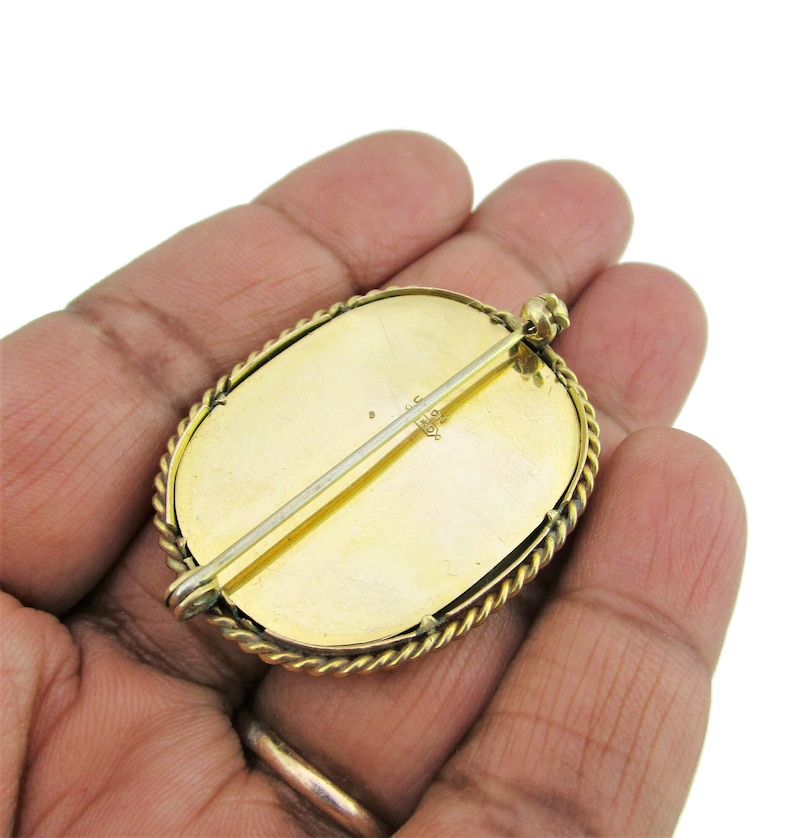 Puede incluir: Broche ovalada de oro con un borde de cuerda. La parte posterior de la broche tiene un pasador y una marca que dice "1/10 14K".