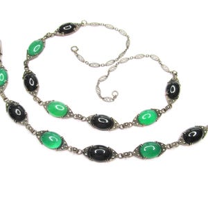 Puede incluir: Un collar y una pulsera de plata con piedras ovaladas negras y verdes. Las piedras est&aacute;n engastadas en un marco de plata con peque&ntilde;os detalles plateados.