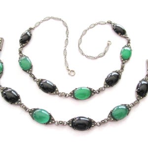 Puede incluir: Un collar vintage de plata con piedras ovaladas negras y verdes. El collar est&aacute; hecho de una cadena delicada con un dise&ntilde;o de filigrana. Las piedras est&aacute;n engastadas en plata y est&aacute;n rodeadas de peque&ntilde;as piedras brillantes.