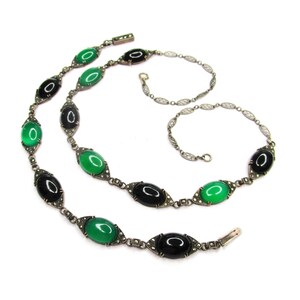 Puede incluir: Un collar de plata con piedras ovaladas negras y verdes. El collar est&aacute; hecho de una cadena delicada con peque&ntilde;as cuentas de plata.