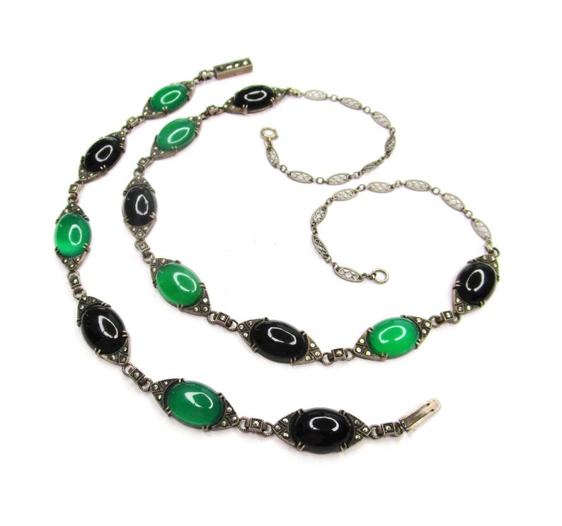 Puede incluir: Un collar de plata con piedras ovaladas negras y verdes. El collar est&aacute; hecho de una cadena delicada con peque&ntilde;as cuentas de plata.