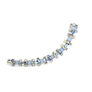 Puede incluir: Un brazalete delicado con una cadena plateada y pedrer&iacute;a azul y transparente iridiscente. El brazalete presenta un patr&oacute;n repetitivo de piedras peque&ntilde;as y grandes.