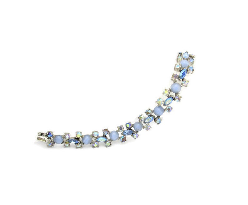 Puede incluir: Un brazalete delicado con una cadena plateada y pedrer&iacute;a azul y transparente iridiscente. El brazalete presenta un patr&oacute;n repetitivo de piedras peque&ntilde;as y grandes.