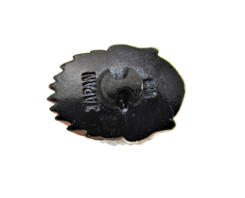 May include: Black button with a white design and the word "JAPAN" printed on the back.