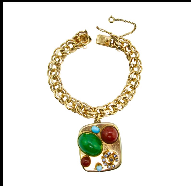 May include: A gold chain bracelet with a square charm featuring a cluster of colorful stones, including green, red, blue, and white.