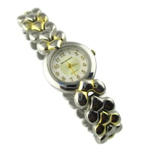 May include: A silver and gold tone Milan quartz wristwatch with a white face and black numbers. The watch has a linked band.