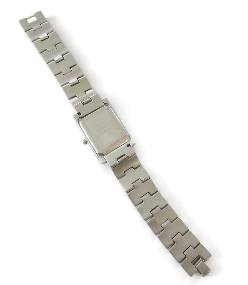 May include: A silver watch with a square face and a silver metal band.