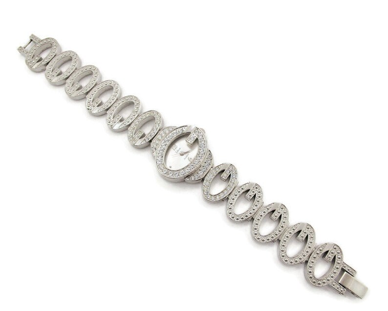 May include: A silver watch with a white face and a bracelet made of interlocking oval links, each set with small clear stones.