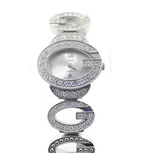 May include: Silver-toned wristwatch with a white face and crystal accents. The watch face features the text "Colezer Quartz" and the band is made up of interlocking "G" letters.