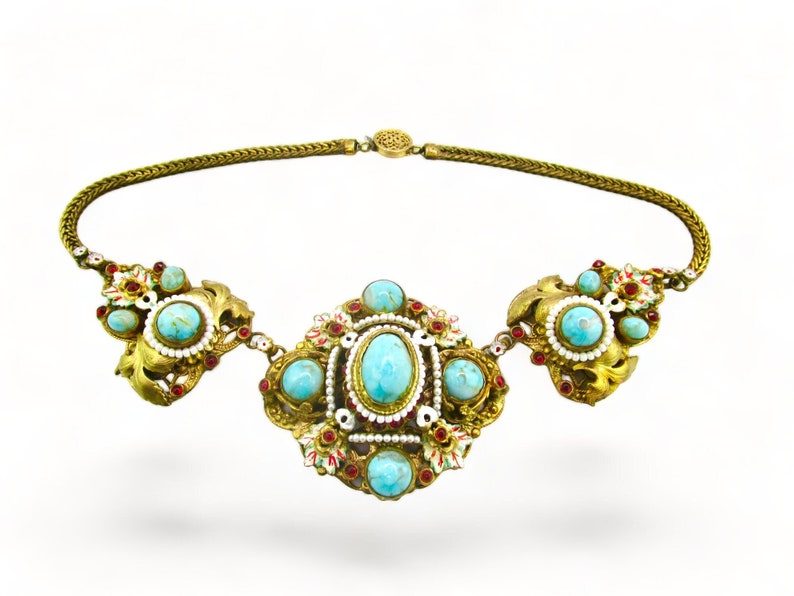 May include: A gold necklace with a chain and three ornate pendants. Each pendant is decorated with turquoise and red gemstones, white beads, and gold filigree.