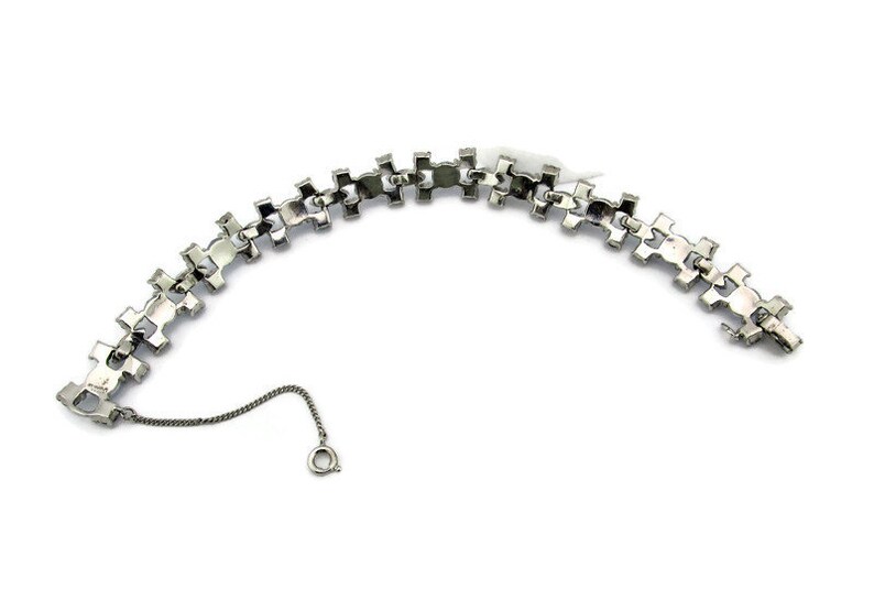 Puede incluir: Un brazalete de tono plateado con un dise&ntilde;o de cadena de eslabones. El brazalete est&aacute; hecho de metal y tiene un cierre de broche.
