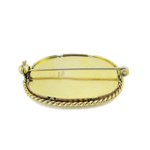 Puede incluir: Broche ovalada dorada con un borde de cuerda y un pasador en la parte posterior. La parte posterior de la broche est&aacute; marcada con "ITALY 18K GOLD".