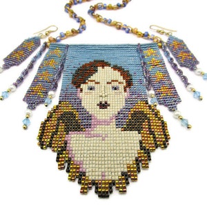 May include: A beaded necklace and earrings set featuring a portrait design. The necklace has a light blue background with a pixelated face. The earrings and necklace chain have gold, blue, and purple beads. The earrings have dangling beads.