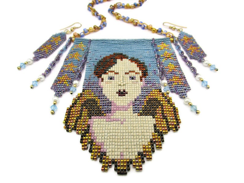 May include: A beaded necklace and earrings set featuring a portrait design. The necklace has a light blue background with a pixelated face. The earrings and necklace chain have gold, blue, and purple beads. The earrings have dangling beads.