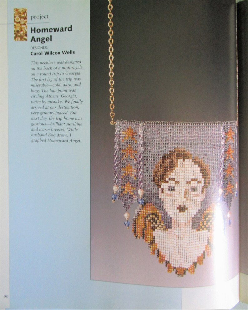 May include: A beaded necklace featuring a portrait of a woman with glasses, framed by a rectangular design with orange and purple accents. The necklace is suspended from a gold chain. The text "Homeward Angel" is visible.