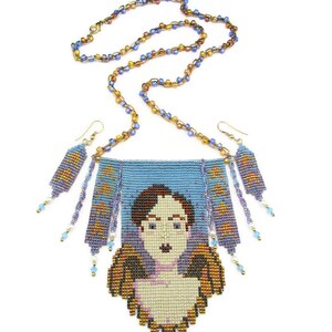 May include: A beaded necklace and earring set featuring a portrait design. The necklace has a blue background with a pixelated face and angel wings. The earrings and necklace chain are made of small, colorful beads.