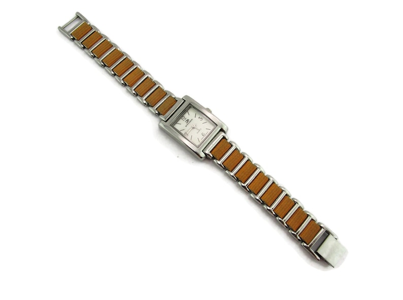 May include: A silver watch with a square face and a brown wood-look band.