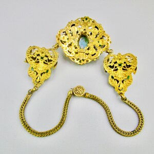Peut inclure: Un collier en filigrane dor&eacute; avec un pendentif en pierre verte et deux fermoirs assortis. Le collier est compos&eacute; d'une cha&icirc;ne d&eacute;licate avec un design tress&eacute;.
