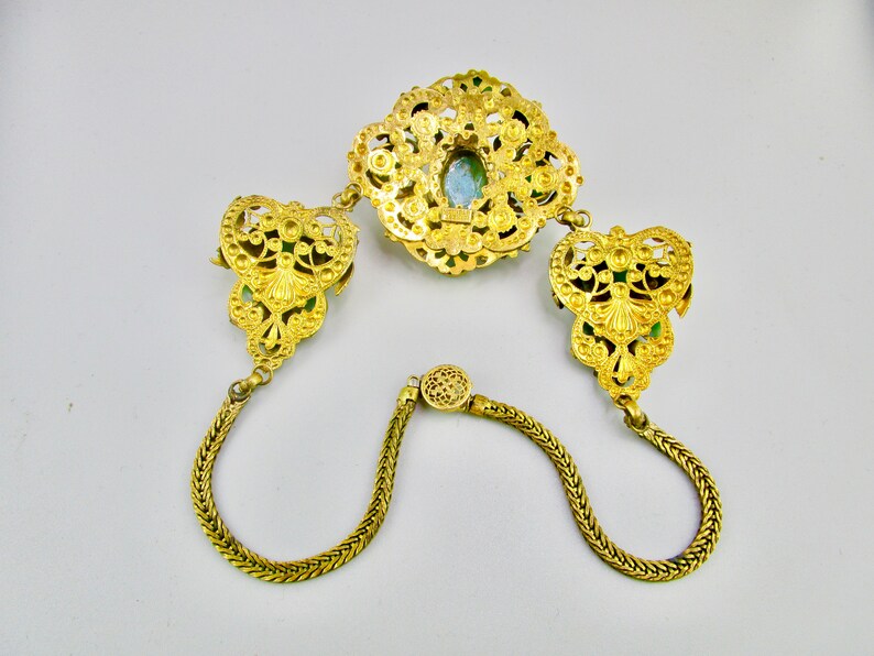 Peut inclure: Un collier en filigrane dor&eacute; avec un pendentif en pierre verte et deux fermoirs assortis. Le collier est compos&eacute; d'une cha&icirc;ne d&eacute;licate avec un design tress&eacute;.