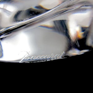 May include: Close-up of a clear glass object with the word "Baccarat" etched on the bottom.