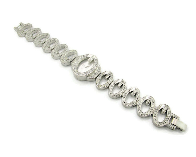 May include: A silver watch with a white face and a bracelet made of interlocking oval links, each set with small clear stones.
