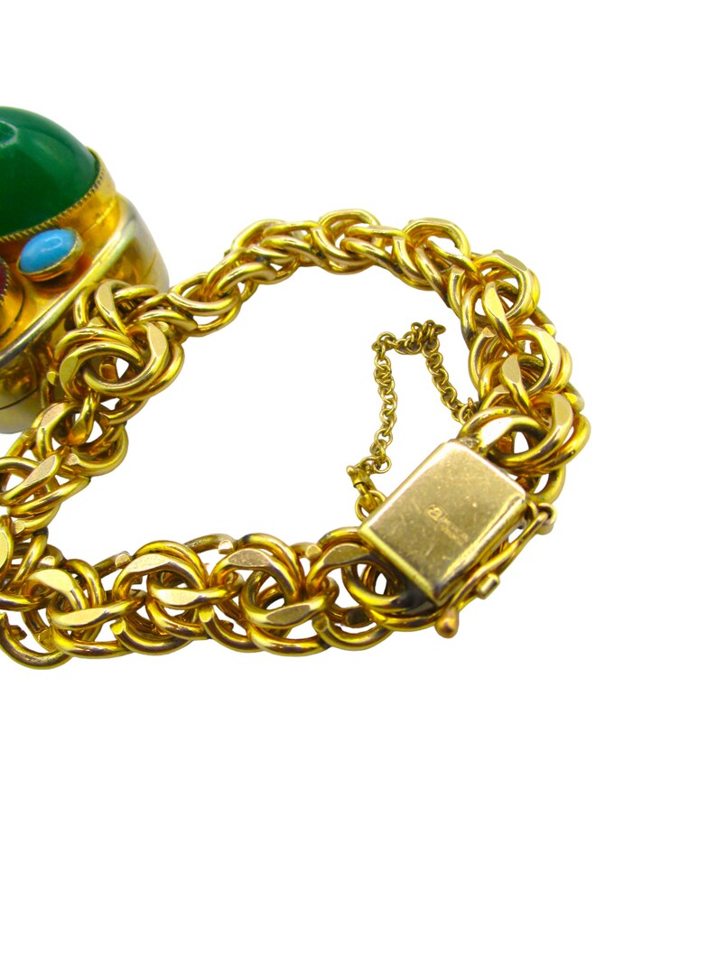 May include: A gold chain bracelet with a large green, blue, and red gemstone pendant. The bracelet has a lobster claw clasp.