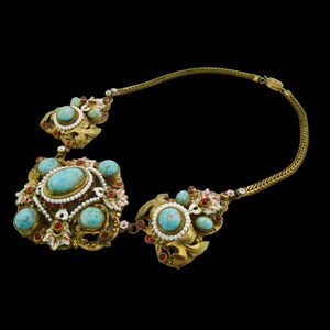 Peut inclure: Un collier en or avec des pierres turquoise et rouges. Le collier a une cha&icirc;ne et trois pendentifs aux motifs complexes.
