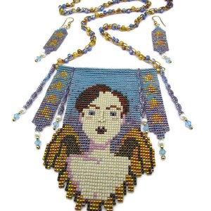 May include: A beaded necklace and earring set featuring a portrait of a person with wings. The necklace has a blue pendant with a face and gold and brown wings. The earrings and necklace chain are made of small, colorful beads.