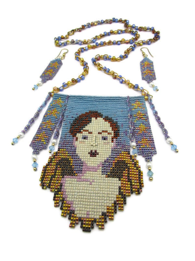 May include: A beaded necklace and earring set featuring a portrait of a person with wings. The necklace has a blue pendant with a face and gold and brown wings. The earrings and necklace chain are made of small, colorful beads.