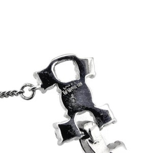 Puede incluir: Collar de cadena de plata con un dije de plata en forma de una letra estilizada 'R'. El dije tiene la palabra 'ROMA' inscrita en &eacute;l.