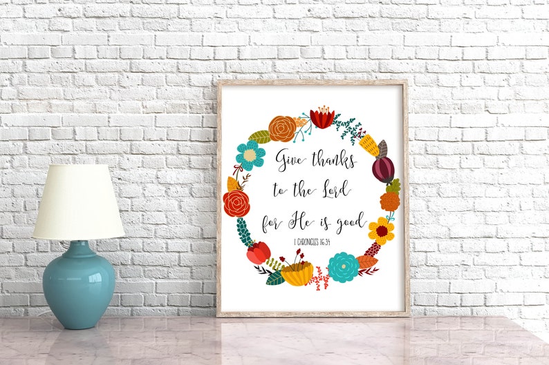 May include: A printable wall art design featuring a floral wreath with colorful flowers and leaves. The wreath surrounds the text "Give thanks to the Lord for He is good" with the scripture reference "1 Chronicles 16:34".