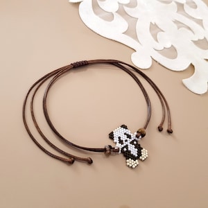 May include: A brown cord bracelet with a beaded panda charm. The panda is black and white with brown bead accents.