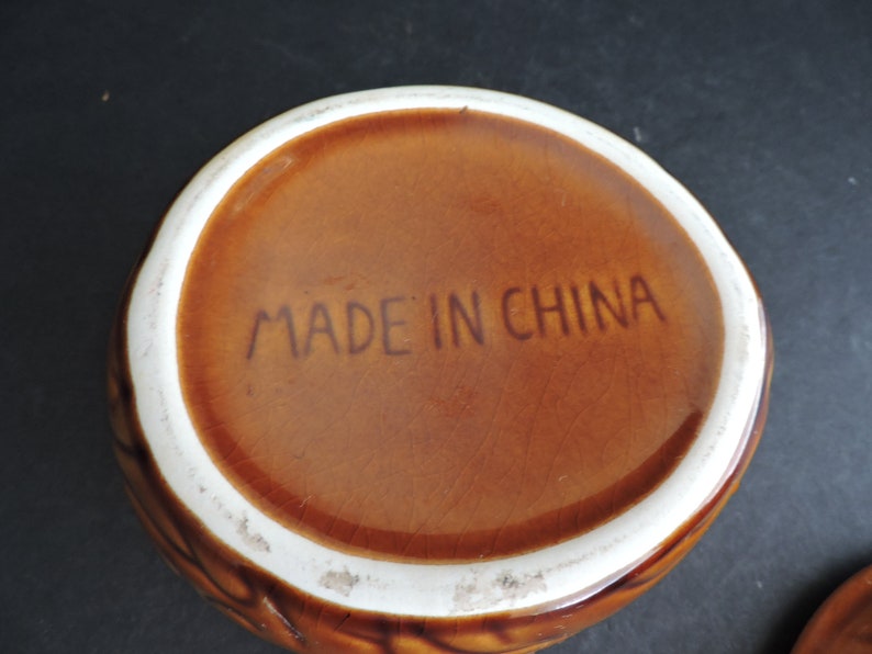 May include: A brown ceramic bowl with a textured exterior and a white rim. The words "MADE IN CHINA" are printed in brown on the interior base of the bowl. The bowl is likely vintage.