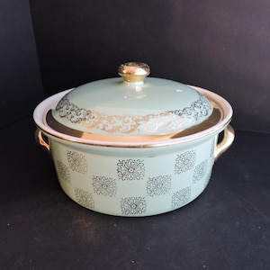 Może przedstawiać: Wintage, miętowy zielony naczynie do zapiekania z pokrywką. Naczynie posiada złote wykończenia i kwiatowy wzór. Pokrywka ma złoty uchwyt. Uchwyty są złote. Dekoracyjny element wyposażenia kuchni.