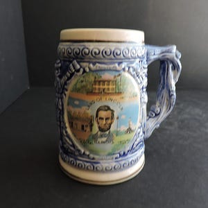 May include: A set of three ceramic mugs with a speckled, matte finish. The mugs are in shades of cream, light gray, and dark gray. Each mug has a simple, minimalist design and a rounded handle.