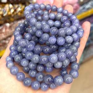 Può includere: Una collana di perle di pietre preziose blu, probabilmente di topazio blu, disposte in un motivo circolare. Le perle sono lisce e lucidate, di colore blu chiaro.