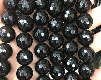 May include: A strand of black faceted gemstone beads. The beads are round and have a hexagonal pattern.