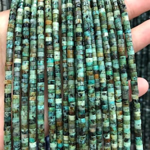May include: A strand of turquoise beads, each bead is a small cylinder with a mottled green and brown pattern.