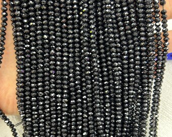 May include: A strand of black faceted glass beads. The beads are small and round, with a shiny finish.