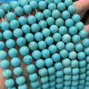 May include: A strand of turquoise blue round beads. The beads are smooth and polished, with a slight variation in color and texture.