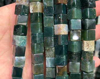 May include: A strand of green, brown, and white agate gemstone beads. The beads are cube shaped and have a polished finish.