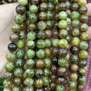 May include: A strand of green and brown gemstone beads. The beads are round and have a smooth, polished finish.