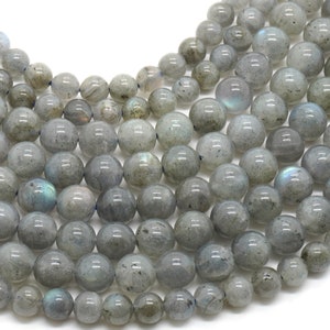 May include: A strand of round, gray labradorite gemstone beads. The beads have a smooth, polished finish and a subtle iridescent sheen.