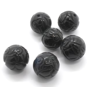 May include: Six black round beads with intricate carved designs. The beads are smooth and polished.